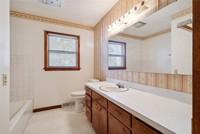 bathroom with a bath, a healthy amount of sunlight, vanity, and toilet