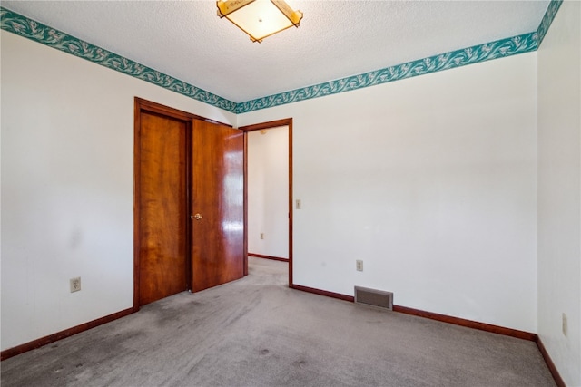 carpeted spare room featuring a textured ceiling