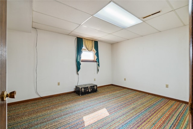 basement with a paneled ceiling and carpet