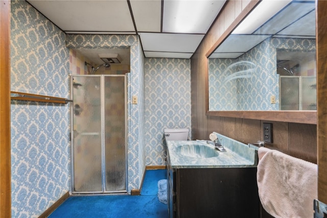 bathroom with vanity, a drop ceiling, a shower with shower door, and toilet