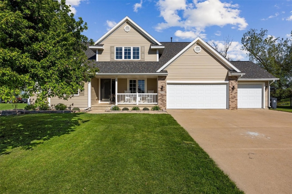 view of front facade with a garage, a porch, and a front lawn