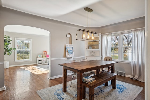 dining area featuring a notable chandelier, a healthy amount of sunlight, and dark hardwood / wood-style flooring