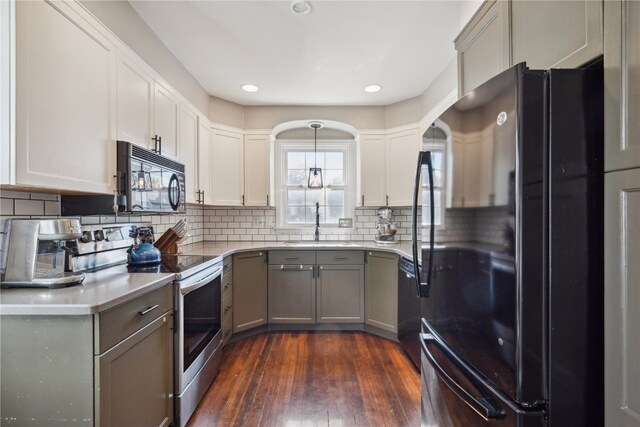 kitchen featuring tasteful backsplash, black appliances, sink, pendant lighting, and dark hardwood / wood-style floors