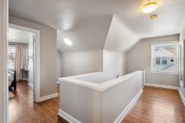 corridor with vaulted ceiling and hardwood / wood-style flooring