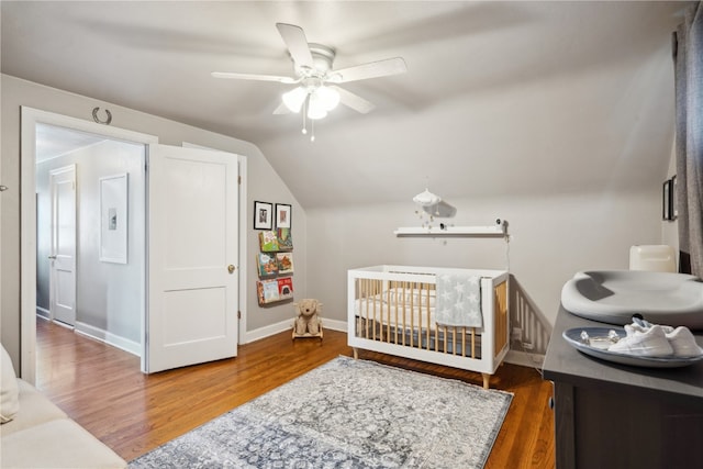 bedroom featuring ceiling fan, wood-type flooring, lofted ceiling, and a crib