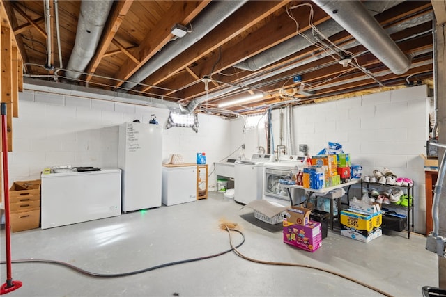 basement with refrigerator, sink, washing machine and clothes dryer, and white refrigerator