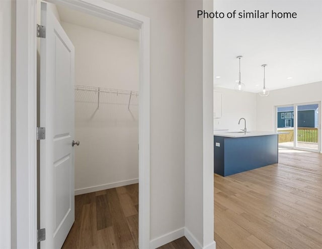 hall with baseboards, light wood-style flooring, and a sink