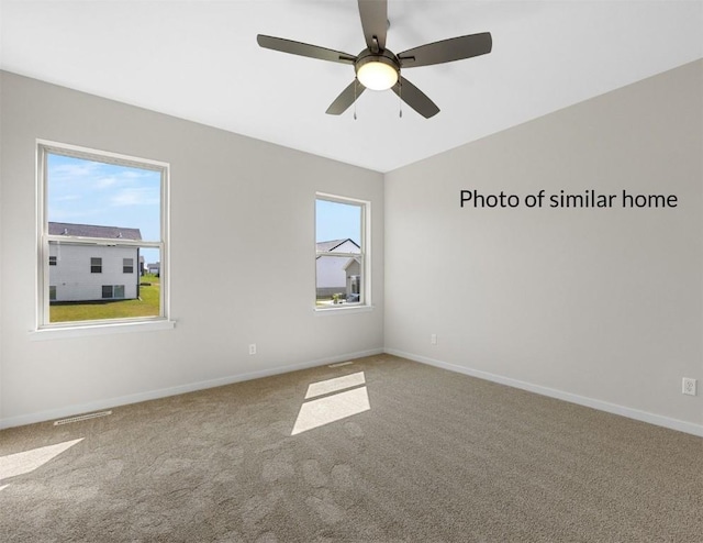 carpeted empty room with visible vents, ceiling fan, and baseboards