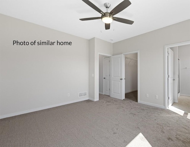 unfurnished bedroom featuring carpet flooring, a walk in closet, visible vents, and baseboards