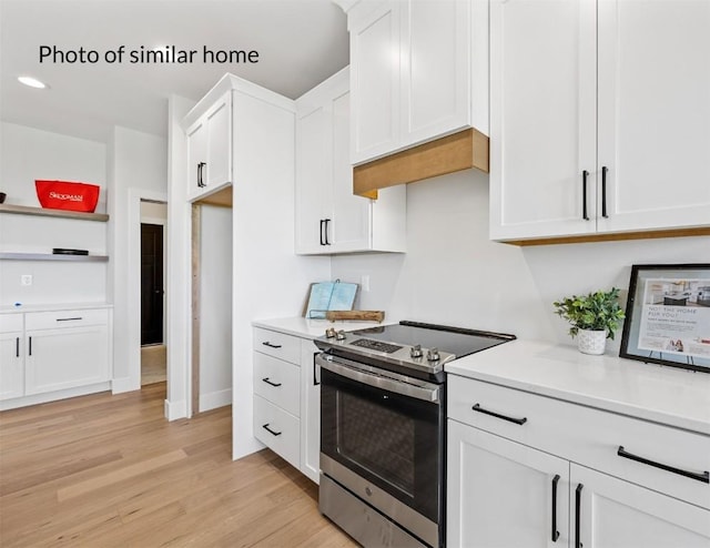 kitchen featuring open shelves, light countertops, light wood-style flooring, electric range, and white cabinetry