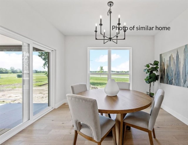 dining space featuring a chandelier, a wealth of natural light, light wood-style flooring, and baseboards