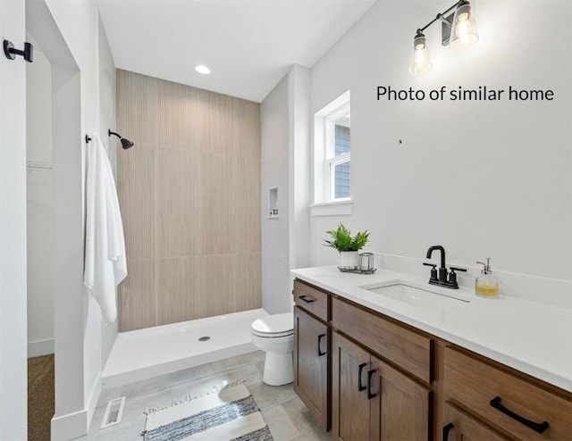 full bathroom featuring toilet, visible vents, a tile shower, and vanity