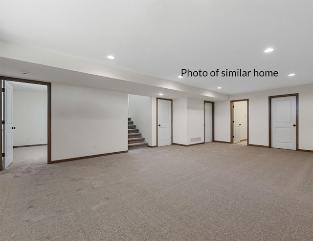 finished basement with baseboards, stairway, light colored carpet, and recessed lighting