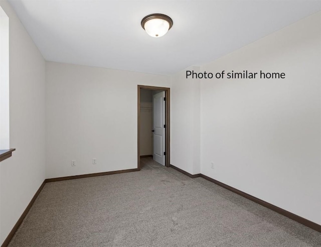 spare room with light carpet and baseboards