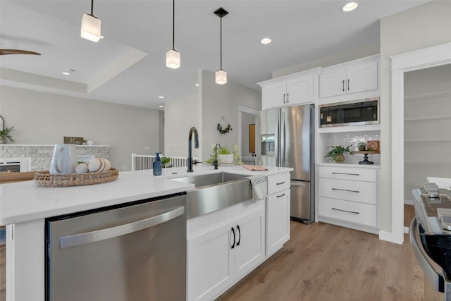 kitchen with light hardwood / wood-style flooring, hanging light fixtures, stainless steel appliances, sink, and white cabinetry