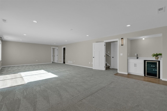 unfurnished living room with wine cooler, bar, and light carpet