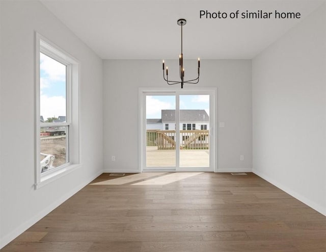 unfurnished dining area with hardwood / wood-style flooring and an inviting chandelier