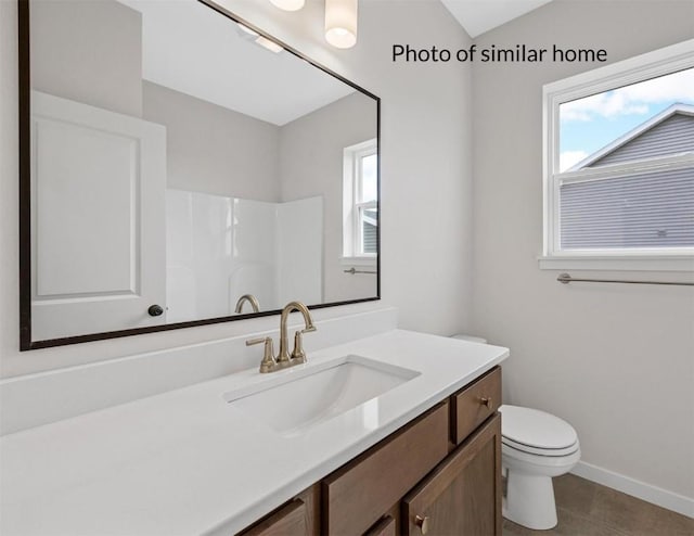 bathroom featuring tile patterned flooring, vanity, toilet, and walk in shower