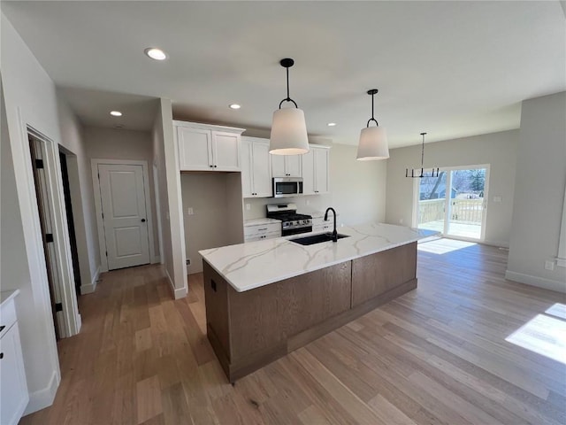 kitchen with a sink, white cabinets, light wood-style flooring, and stainless steel appliances