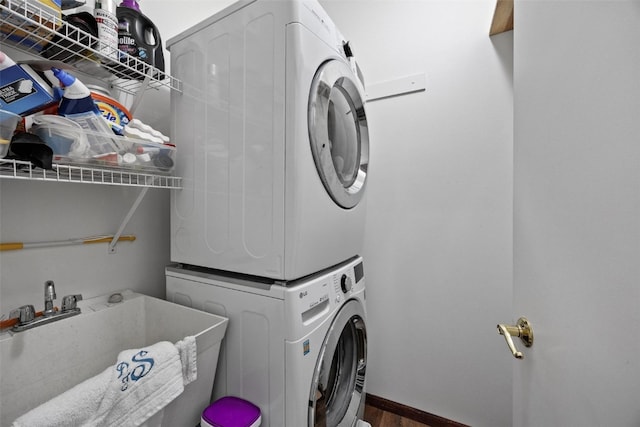 washroom featuring sink, stacked washer / dryer, and dark wood-type flooring