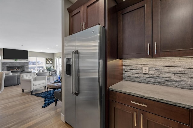 kitchen with light hardwood / wood-style floors, light stone countertops, dark brown cabinets, and high quality fridge