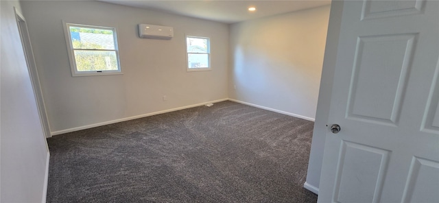 spare room with a wall mounted AC and dark colored carpet