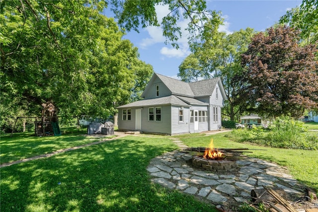 back of house featuring an outdoor fire pit, a patio, and a lawn