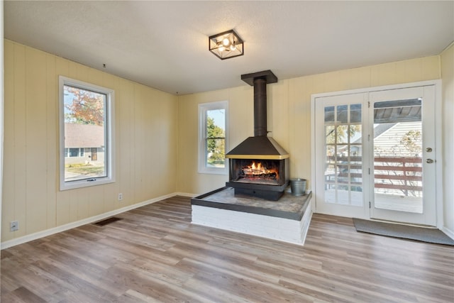 living room featuring plenty of natural light, a wood stove, and light hardwood / wood-style floors