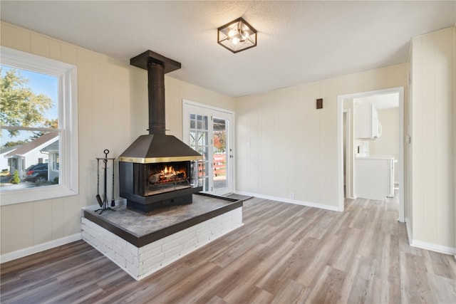 unfurnished living room with hardwood / wood-style flooring, a wood stove, and a textured ceiling