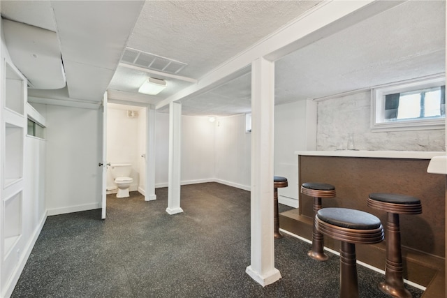 basement featuring bar area and a textured ceiling