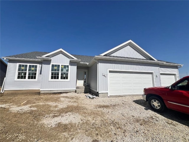 ranch-style house with a garage, driveway, and roof with shingles