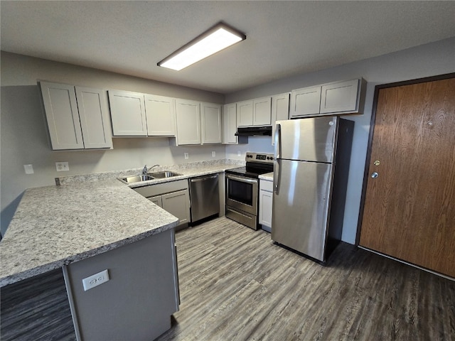 kitchen with kitchen peninsula, hardwood / wood-style floors, appliances with stainless steel finishes, a textured ceiling, and sink