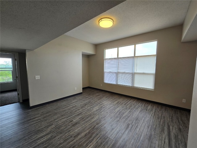 unfurnished room featuring a textured ceiling, plenty of natural light, and dark hardwood / wood-style flooring