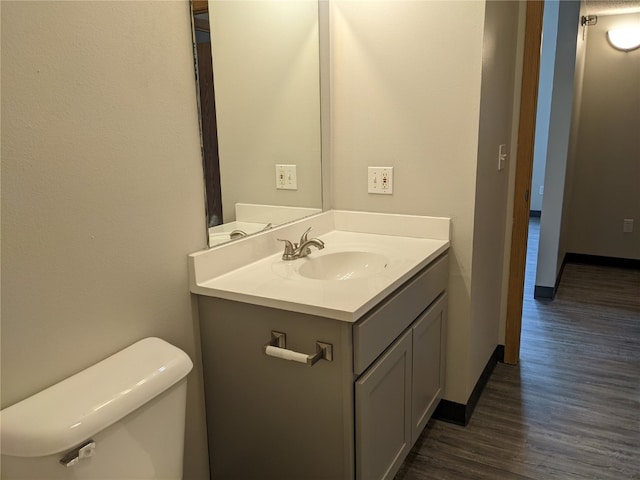 bathroom with toilet, hardwood / wood-style floors, and vanity