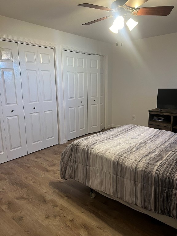 bedroom with multiple closets, wood-type flooring, and ceiling fan