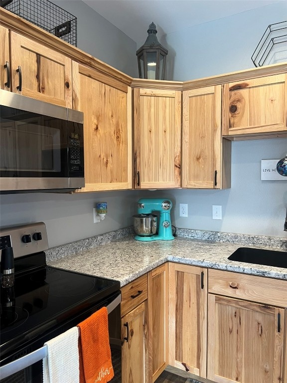 kitchen featuring light stone counters, appliances with stainless steel finishes, and sink