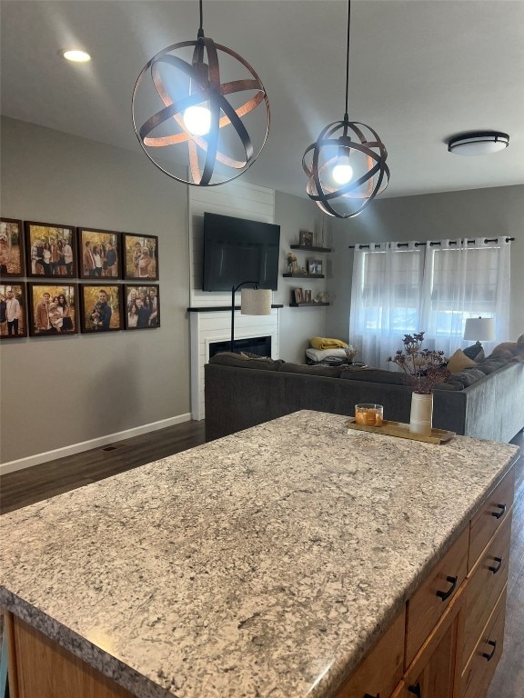 kitchen featuring dark wood-type flooring, light stone countertops, and hanging light fixtures