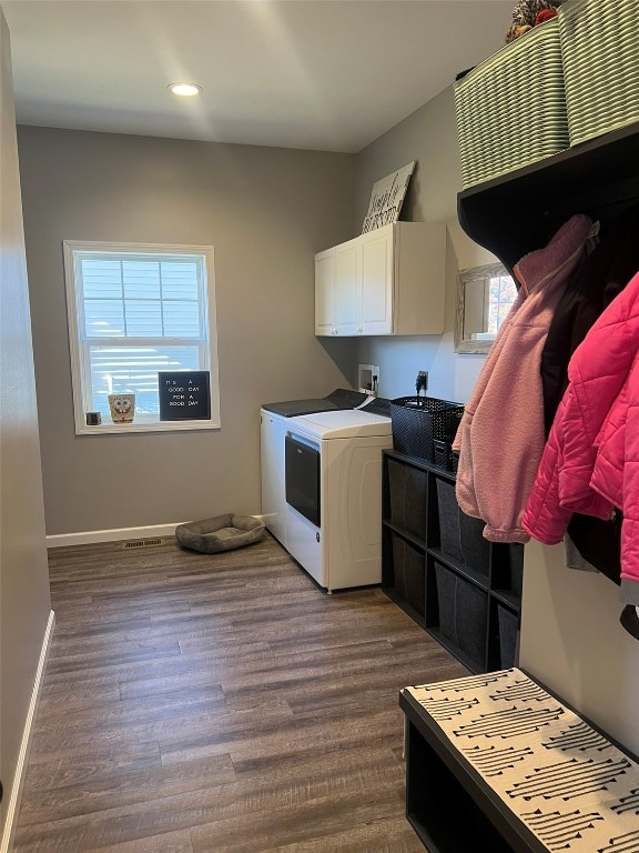 clothes washing area with dark wood-type flooring, independent washer and dryer, and cabinets