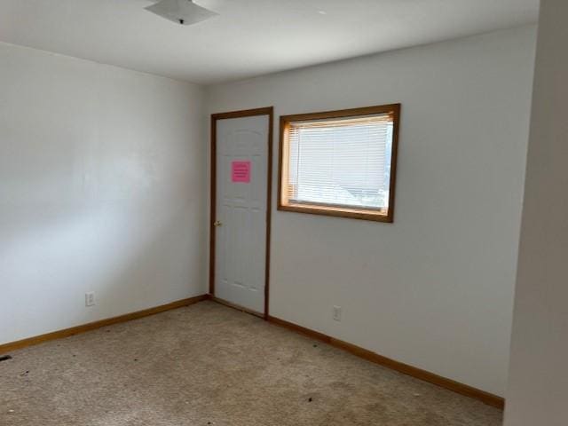 unfurnished room featuring baseboards and light colored carpet