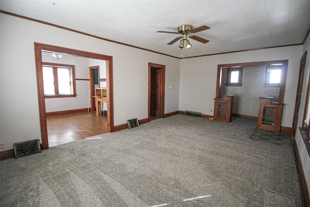 spare room with ceiling fan, ornamental molding, a wealth of natural light, and dark colored carpet