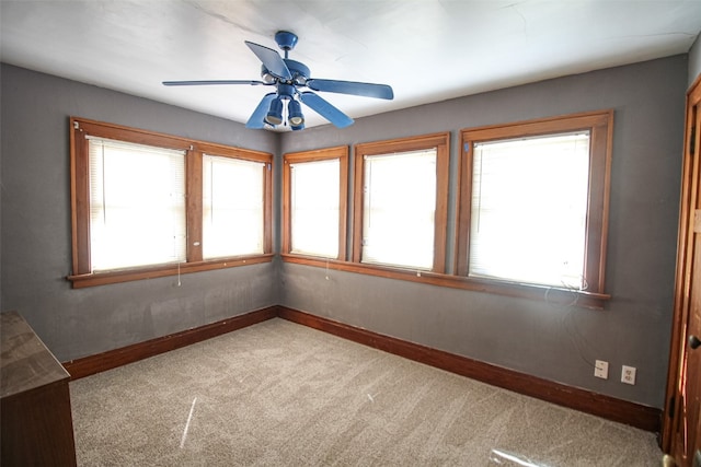 carpeted spare room featuring a wealth of natural light and ceiling fan