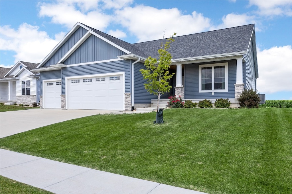 craftsman-style home with a front yard, a garage, and cooling unit