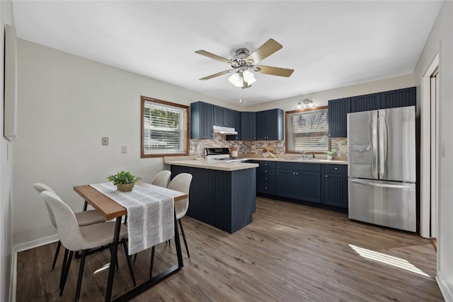 kitchen with stainless steel refrigerator with ice dispenser, wood-type flooring, kitchen peninsula, sink, and black range