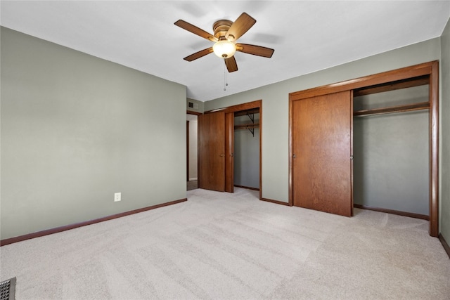 unfurnished bedroom with light carpet, two closets, and ceiling fan