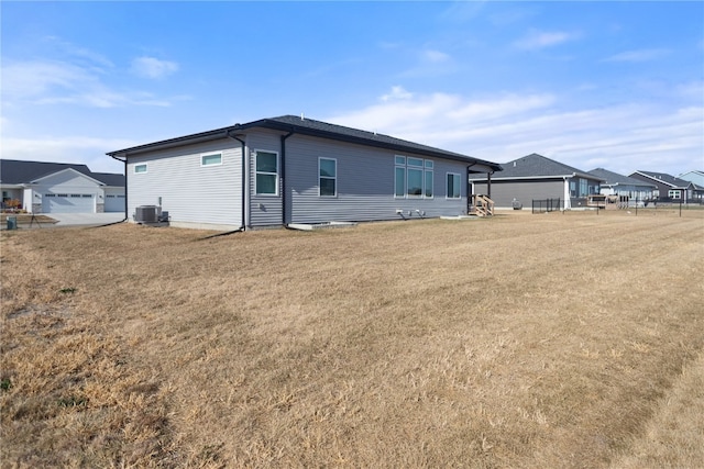 rear view of house featuring central air condition unit and a lawn