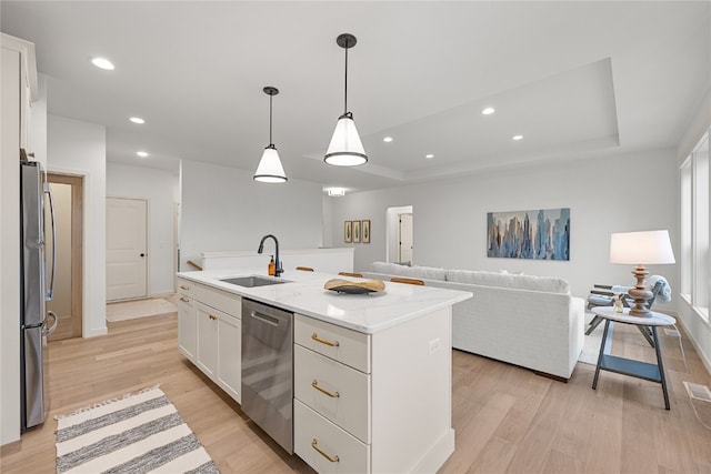 kitchen featuring an island with sink, stainless steel appliances, sink, white cabinetry, and light hardwood / wood-style floors