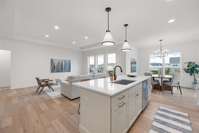 kitchen featuring light wood-type flooring, sink, pendant lighting, and a center island with sink