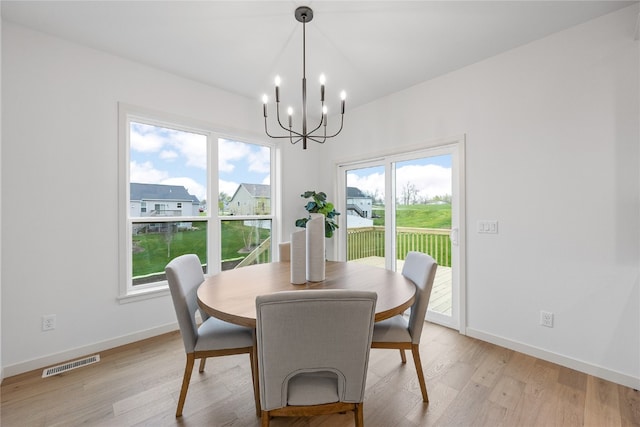 dining area with a notable chandelier, a healthy amount of sunlight, and light wood-type flooring