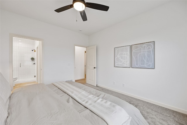 bedroom with ceiling fan, light colored carpet, and ensuite bath