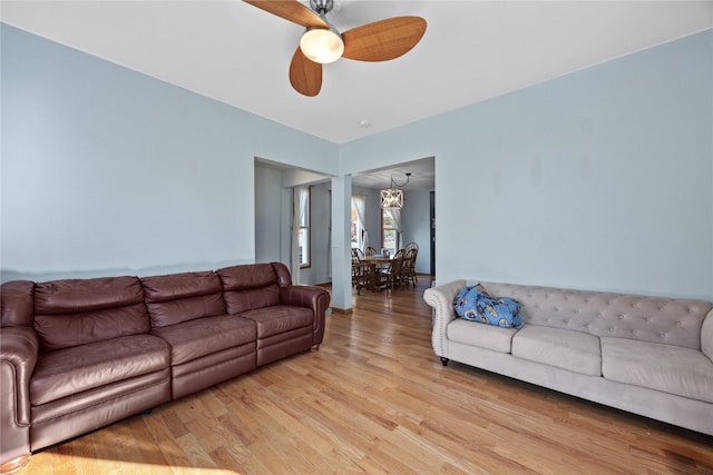 living room featuring light hardwood / wood-style flooring and ceiling fan with notable chandelier